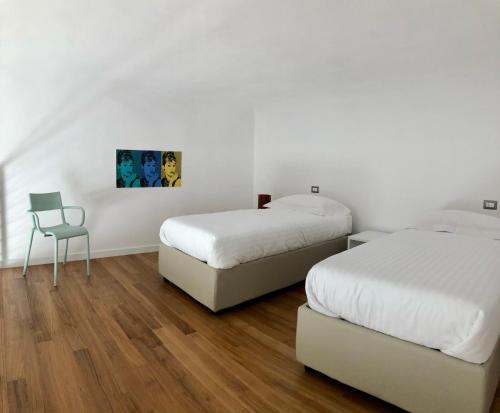 塔兰托Lo Schiaccianoci B&B的白色客房的两张床和椅子