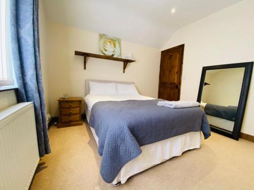 雷克瑟姆Merlin House的一间卧室配有一张带蓝色毯子和镜子的床