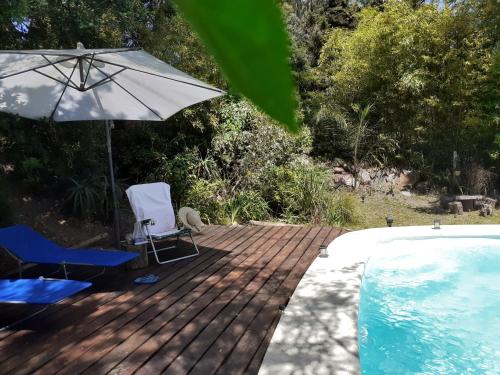 埃斯特角城Los Mochos Portezuelo的游泳池旁的甲板配有两把椅子和一把遮阳伞