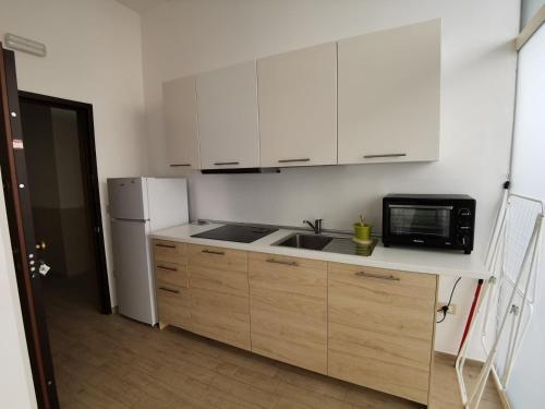 塔兰托All' Ombra del Faro - Mini Apartments的厨房配有白色橱柜、水槽和微波炉