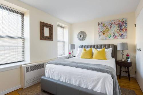 布鲁克林Elegant and Comfortable Stay的白色卧室配有一张带黄色枕头的大床