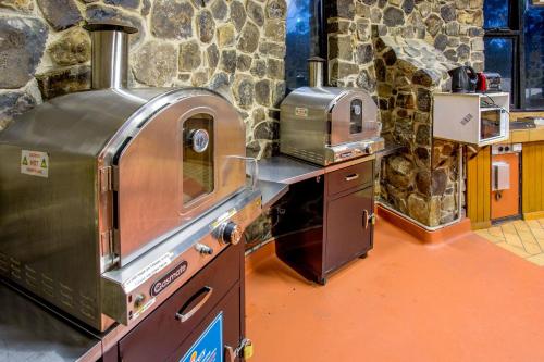 摇篮山Discovery Parks - Cradle Mountain的厨房配有石墙内的2个烤箱