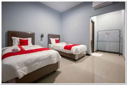 DaresRedDoorz Syariah near T2 Juanda Airport 2的一间卧室配有两张红色和白色床单