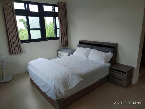 富里青禾軒的卧室配有一张带白色床单的大床和窗户。