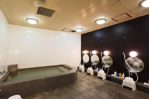 东京汤岛胶囊旅馆（只限男性）的带浴缸、盥洗盆和镜子的浴室