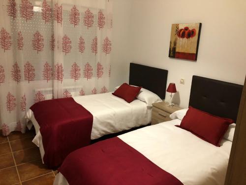 Los NavalucillosAlojamientos El Chorro的一间设有两张红色和白色床单的房间