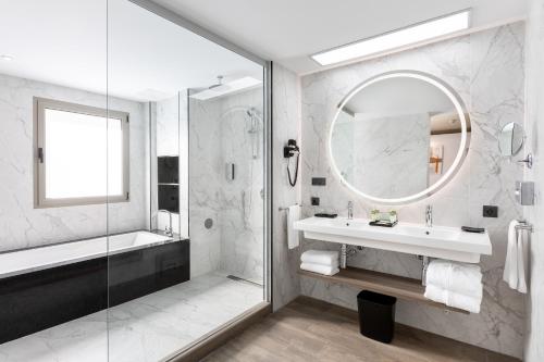 马斯帕洛马斯Hotel Riu Palace Oasis的一间带水槽、淋浴和镜子的浴室