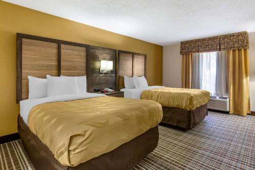 格林斯伯勒Quality Inn & Suites - Greensboro-High Point的酒店客房设有两张床和窗户。