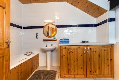 GraiguenamanaghMount Brandon Cottages Graiguenamanagh的一间带水槽、浴缸和镜子的浴室