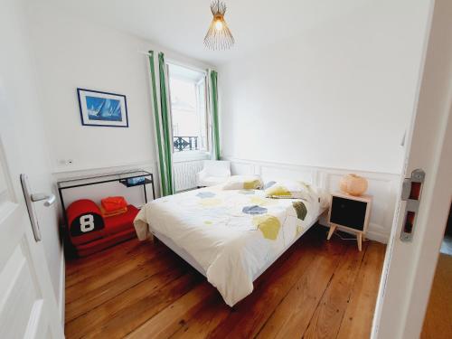 圣马洛Les Sablons - Très Bel Appartement , Lumineux的一间卧室配有一张铺有木地板的白色床单。