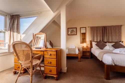 特维德上游的贝里克Manor House Hotel Holy Island的一间卧室设有两张床、一张桌子和一个窗口。