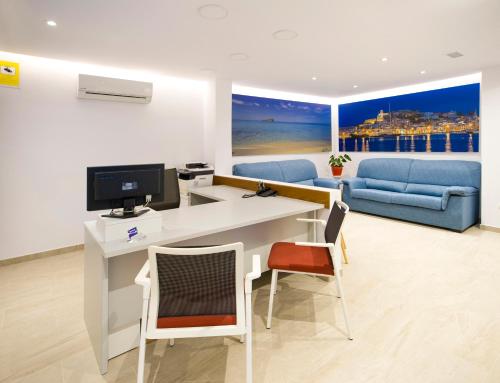 伊维萨镇白色海岸旅馆的客房设有一张桌子、一台电脑和一张沙发