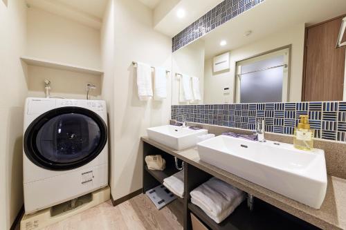 东京MONday Apart Premium AKIHABARA的一间带两个盥洗盆和洗衣机的浴室