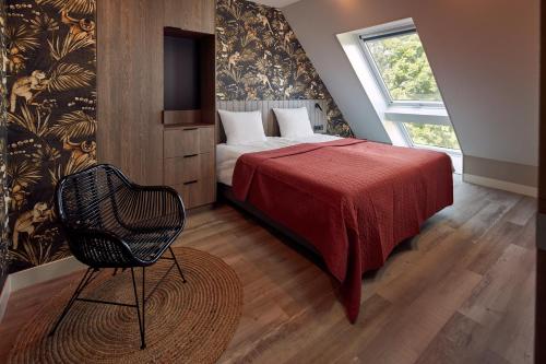 吕伐登Farm house Van der Valk Hotel Leeuwarden的一间卧室配有一张带红色毯子和椅子的床