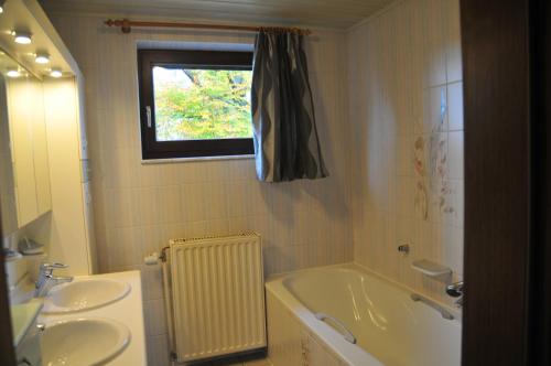 GouvyLa Maison du Bonheur的带浴缸、两个盥洗盆和窗户的浴室