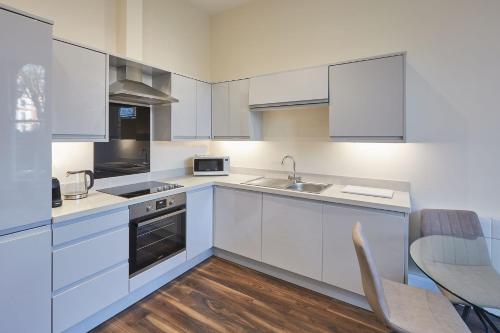 斯卡伯勒Host & Stay - South Cliff Apartment的厨房配有白色橱柜、水槽和桌子