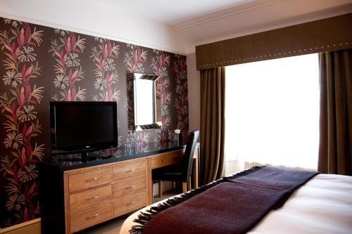 梅尔罗斯陶恩豪斯酒店的一间卧室配有一张床和一张书桌及电视