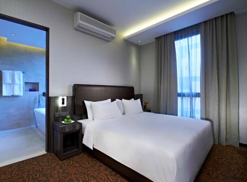 新加坡Aqueen Hotel Kitchener的一间带白色大床的卧室和一间浴室