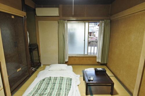 小山市Aikawa Ryokan - Vacation STAY 04180v的一间卧室配有一张床、一张桌子和一个窗户。
