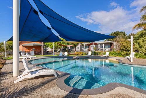 布雷布鲁克Discovery Parks - Melbourne的一个带椅子和蓝伞的游泳池