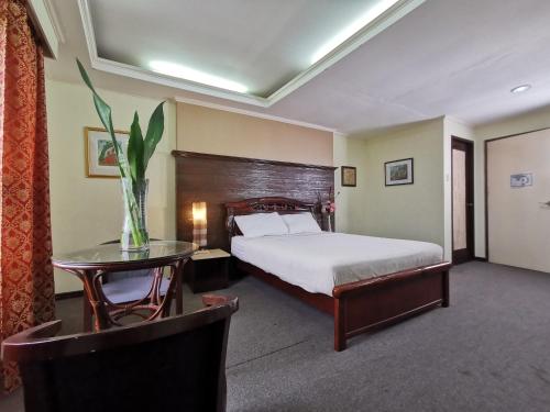 宿务Cebu Hilltop Hotel的一间卧室配有一张床和一张桌子,上面有花瓶