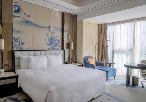 昆明昆明富力万达文华酒店的卧室配有一张白色大床和蓝色画作