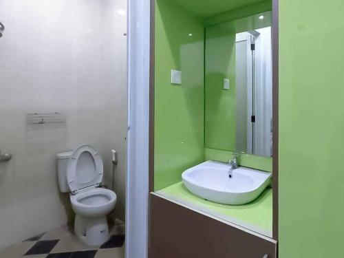 芝勒贡Aimer Guest House Syariah Mitra RedDoorz的绿色浴室设有卫生间和水槽