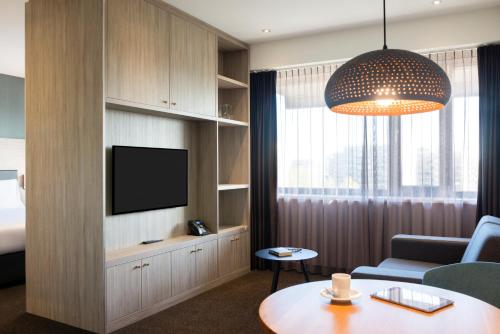 阿姆斯特尔芬阿姆斯特丹城南阿达焦酒店的客厅配有电视、沙发和桌子