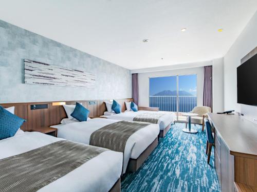 鹿儿岛Art Hotel Kagoshima的一间酒店客房,设有三张床和一台平面电视