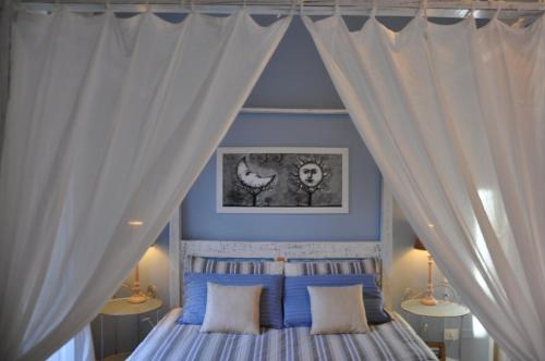 卡利亚里新罗曼蒂克公寓的卧室配有带白色窗帘的天蓬床