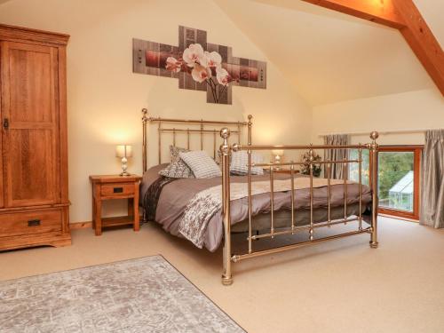蒂弗顿Crooke Barn的一间卧室配有一张床和一个木制橱柜