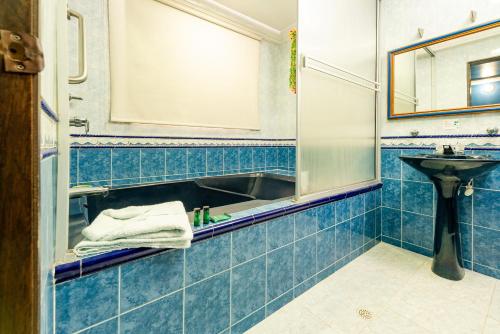 比亚维森西奥Hotel Ayenda Eclipse 1706的蓝色瓷砖浴室设有水槽和镜子