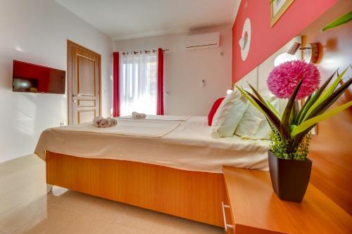 乌尔齐尼普里玛菲拉别墅公寓酒店的一间卧室配有一张带盆栽的大床