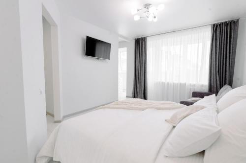 博布鲁伊斯克PaulMarie Apartments on Gor'kogo 41的一间白色卧室,配有床和电视