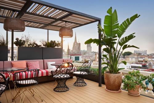 巴塞罗那Kimpton Vividora Hotel, an IHG Hotel的屋顶庭院配有沙发、桌子和植物