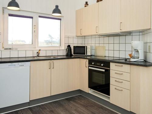森讷维8 person holiday home in Ringk bing的厨房配有白色橱柜和黑色台面