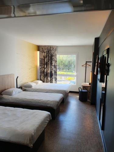 乌伊斯特勒昂B&B HOTEL Ouistreham的酒店客房设有三张床和窗户。