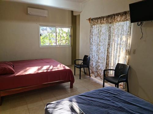 伊斯塔帕普拉亚琳达宾馆的一间卧室设有两张床、两把椅子和窗户。