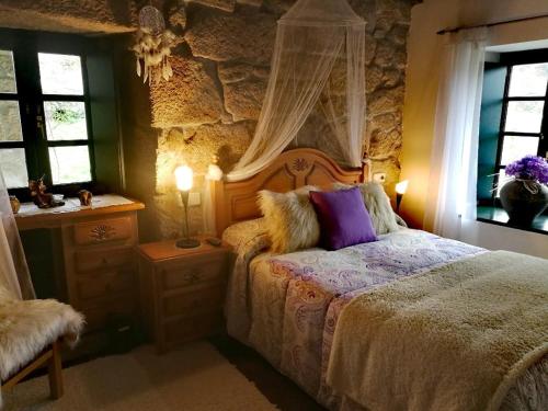 诺盖拉德拉姆Caserio de Fontes的一间卧室设有一张床和石墙