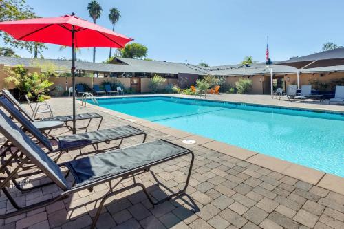 桑蒂Carlton Oaks Lodge, Ascend Hotel Collection的一个带2把躺椅和遮阳伞的游泳池