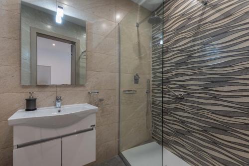 梅利哈White Sands的浴室配有盥洗盆和带镜子的淋浴