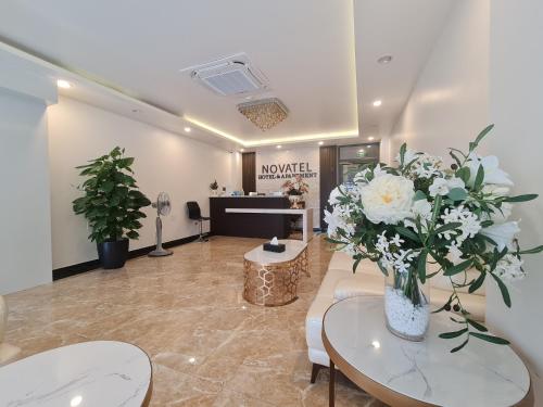 海防Novatel Hotel & Apartment的大堂设有花瓶内白色花卉的等候室