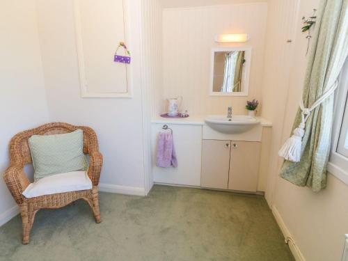 霍利黑德Charming 2 Bed House near Rhoscolyn DISCOUNTS FOR的一间带柳条椅和水槽的浴室