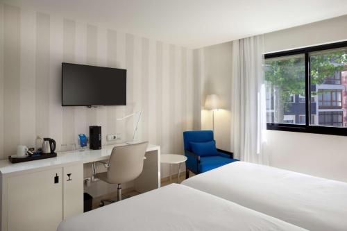 桑坦德NH桑坦德城市酒店的酒店客房设有一张床、一张书桌和一台电视机。