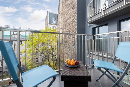 波兹南Apartament City Center Strzelecka by Renters的阳台配有两把椅子和一碗水果(桌子上)。