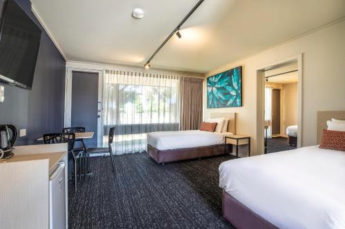 CorioNightcap at Gateway Hotel的酒店客房带两张床和一张桌子以及椅子。