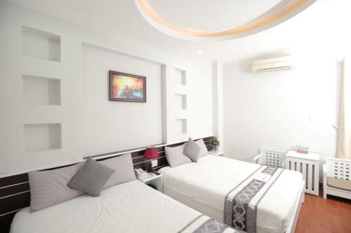 芽庄Nha Trang Pearl Hotel的白色墙壁客房的两张床