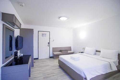 合艾旺季酒店的一间卧室配有一张大床和电视
