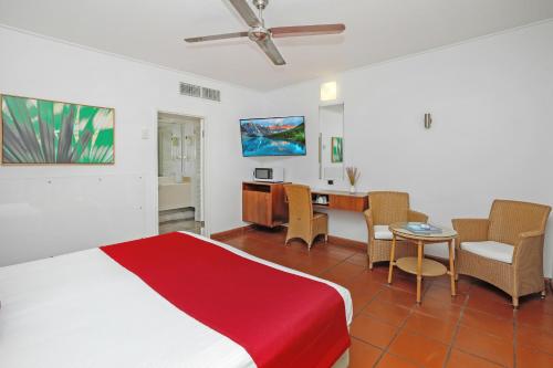 凯恩斯Ramada By Wyndham Cairns City Centre的卧室配有一张床和一张桌子及椅子