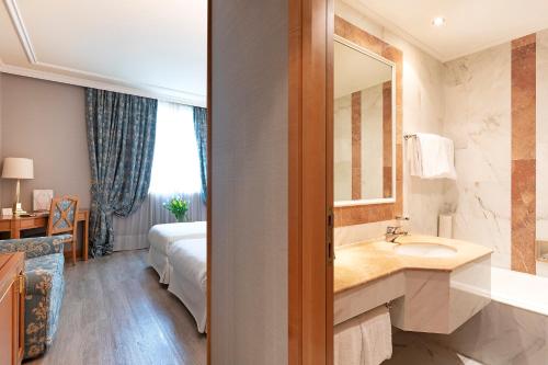 阿萨哥皇家花园酒店的一间带水槽和镜子的浴室以及一张床